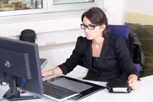 Mujer joven trabajando concentrada en oficina moderna, gestionando múltiples tareas y habilidades