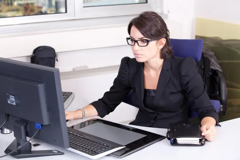 Mujer joven trabajando concentrada en oficina moderna, gestionando múltiples tareas y habilidades