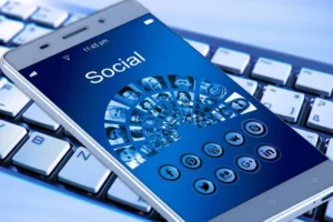 Persona usando celular con íconos de redes sociales, representando el impacto digital en la convivencia y el debate público.