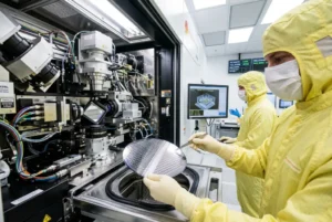 Ingenieros en sala limpia fabricando chips de silicio con maquinaria de alta precisión en entorno industrial.