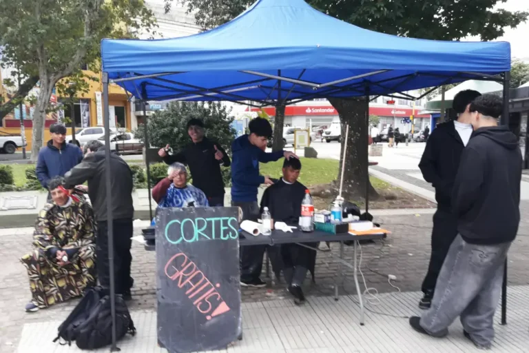 Jóvenes realizan cortes de cabello gratuitos en Plaza 25 de Mayo de Concordia durante una jornada solidaria comunitaria.